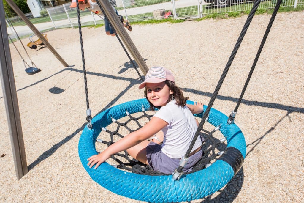 Enfant qui s'amuse à la balançoire sur l'aire de jeux pour les enfants au camping