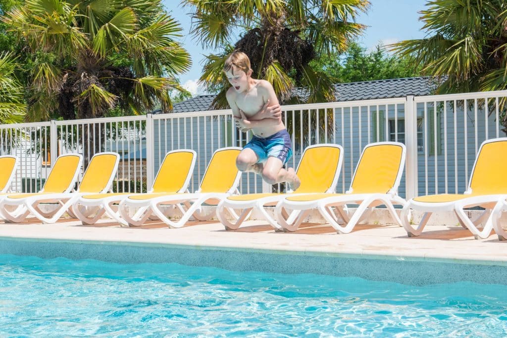 Enfant heureux qui saute dans l'espace aquatique du camping Soleil Levant près de Royan